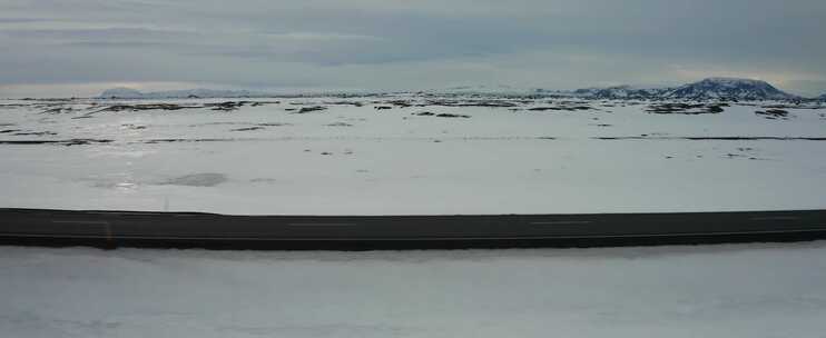 在雪地和山脉天线旁边的道路上行驶的汽车