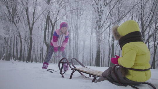 母亲向坐在雪橇上的小孩扔雪