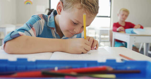 快乐的高加索男孩坐在学校桌子前写作的视频