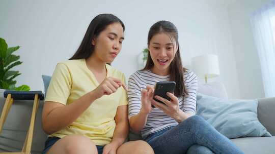 亚洲女性截肢者与漂亮的朋友在家里使用手机。