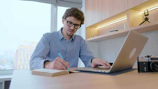 戴眼镜的自由职业者正在家里用笔记本电脑远程工作。远程工作。