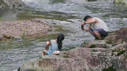 情侣游客在清澈的溪流边拍照打卡