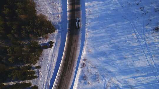 吊杆升降机卡车沿着穿过森林的下雪农村道路行驶