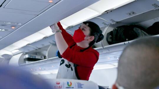 民航航空飞机上，空姐正在帮游客整理行李