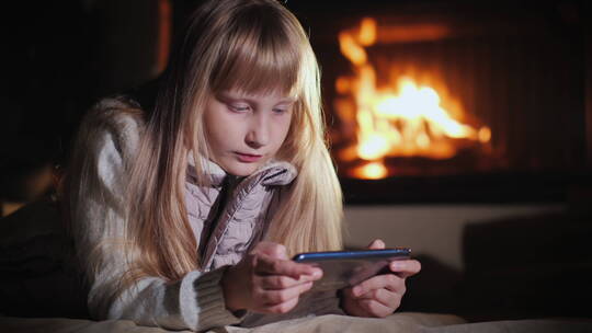 女孩在壁炉前玩手机视频素材模板下载