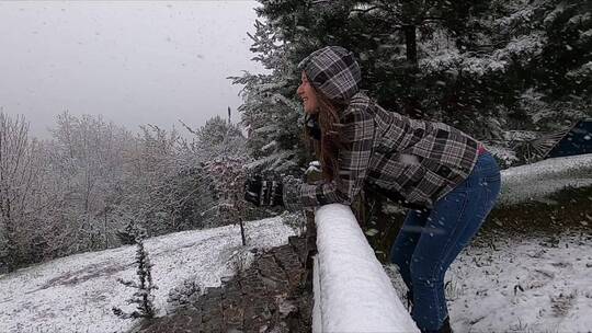 下雪天女人穿着冬季夹克倚在栏杆上