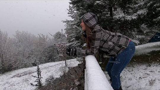 下雪天女人穿着冬季夹克倚在栏杆上视频素材模板下载