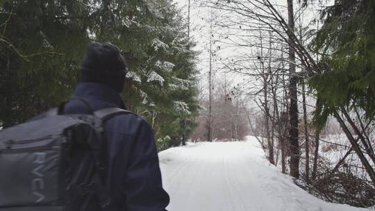 摄影师走在森林里的雪地上