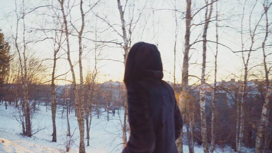 年轻的成年女子独自走在公园的雪地上
