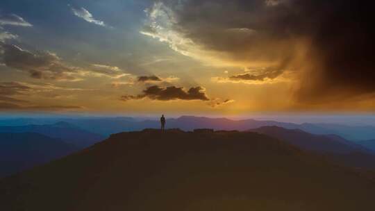 无人机拍摄黄昏时男人站在山顶上
