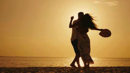 情侣在黄昏沙滩上抱着转圈圈