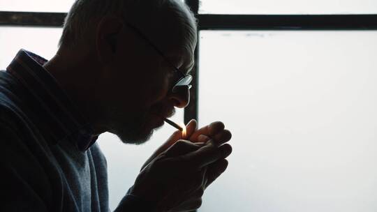在窗前吸烟的男人