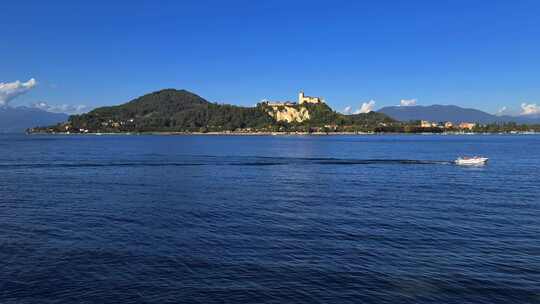 在意大利马焦雷湖平静的湖水中航行的小型摩托艇，后面有安吉拉城堡
