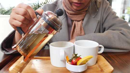 一个女人用透明玻璃倒热凉茶