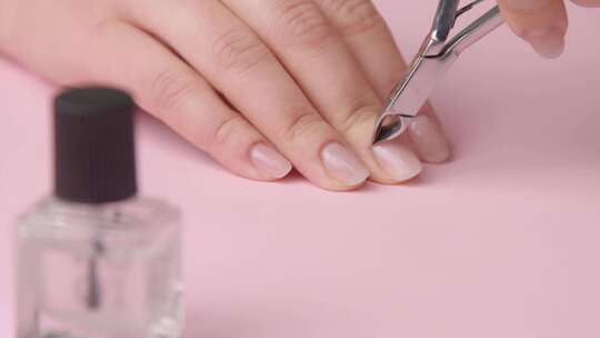 特写女人手放在粉色桌面上修指甲