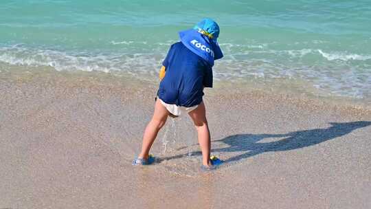海南三亚正在海边沙滩上体验夏天海浪的男孩