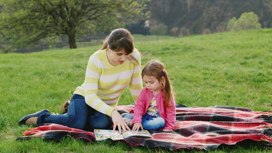小女孩和妈妈一起在草地上读书