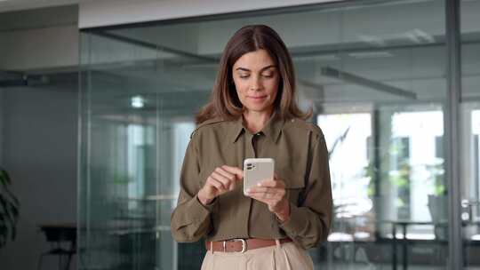 微笑成熟的商务女性手持智能手机站在公司办视频素材模板下载