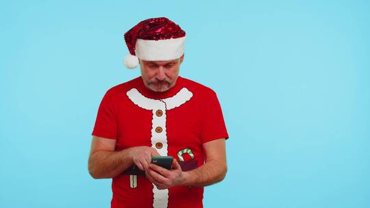 穿着时尚圣诞T恤的人看智能手机做兴奋庆祝的姿势