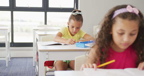 专注于不同女孩坐在学校课桌前学习的视频