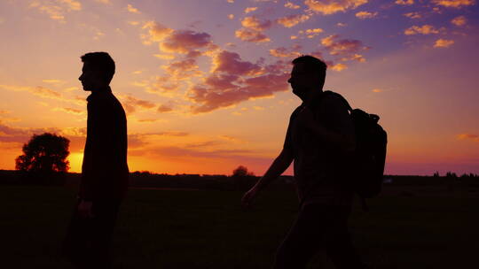 夕阳下父亲和儿子在田野散步的剪影