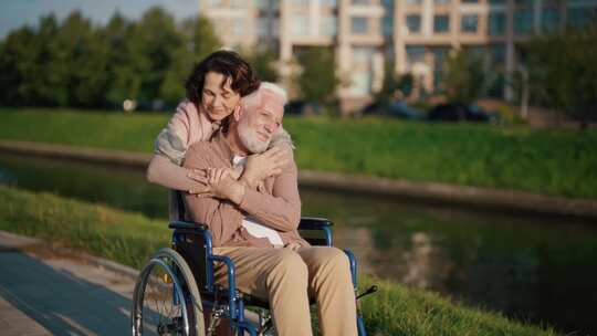 妻子和丈夫坐在轮椅上散步高级快乐的家庭夫