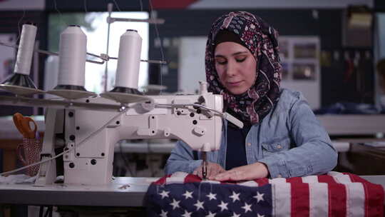 戴头巾缝制美国国旗的女人