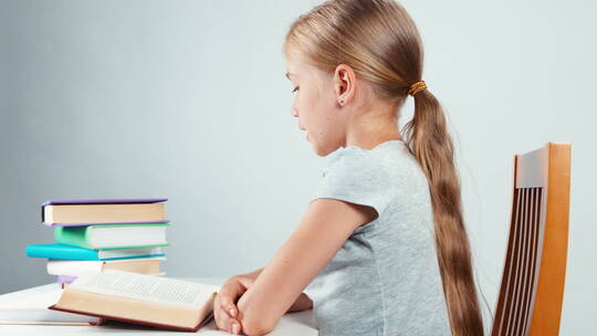 儿童坐在书桌前阅读书籍视频素材模板下载