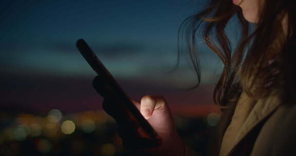 年轻女子在夕阳下看手机