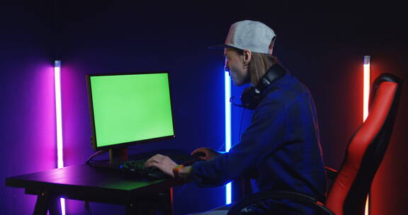 电竞玩家坐在绿幕电脑前打游戏