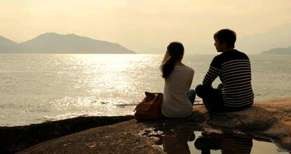 夫妇在海边欣赏日落下的海景