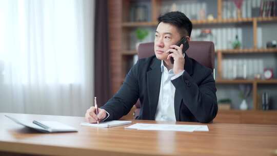 亚洲律师商人处理文书工作文件并打电话。忙