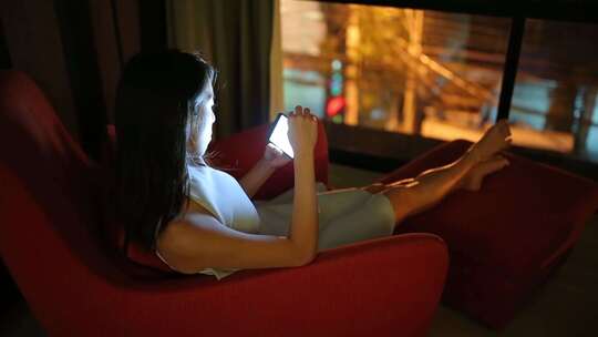 女孩晚上沙发看手机视频素材模板下载