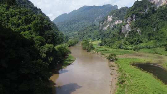 一艘旅游船沿着亚洲山脉和绿林之间的河流航行，环绕丛林