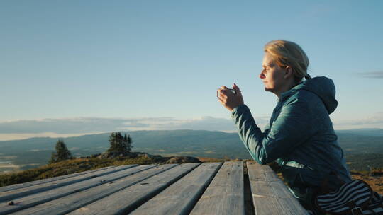 女士坐在高山上的一张桌子上喝茶