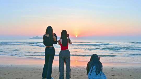 三个亚洲年轻漂亮美女站在大海边拍摄日出