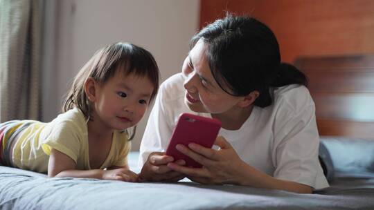 小女孩和妈妈在一起看手机学习宝妈育儿视频素材模板下载