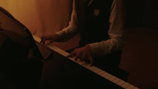 男生在钢琴旁演奏