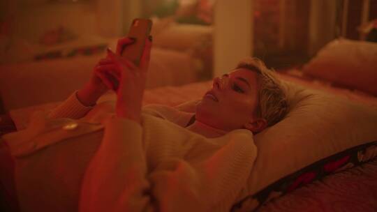 女孩躺在床上玩手机视频素材模板下载