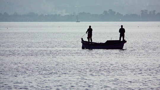 渔民在旧渔船上用鱼竿钓鱼