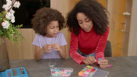 开朗的小黑女儿为儿童手镯选择彩色橡皮筋