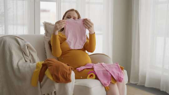 孕妇看着婴儿服装美丽的未来母亲享受分娩看