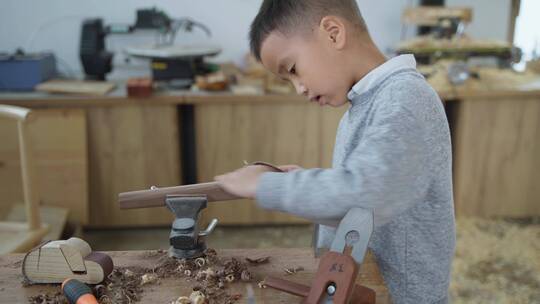 小男孩认真专心独自做木工打磨动手能力强