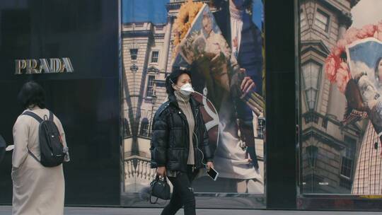 疫情下的成都街头行人戴口罩走过橱窗广告牌