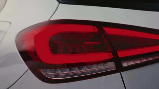 汽车闪亮的红色尾灯特写，油漆表面的光反射