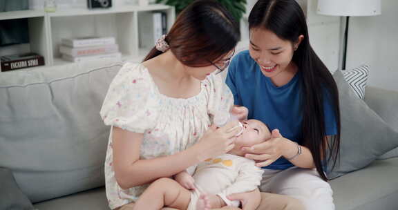 两个年轻的亚洲女人在家里开心地和一个婴儿