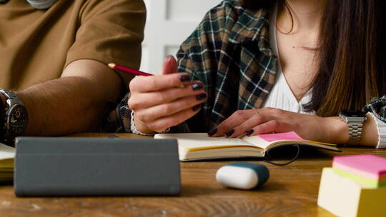 学生拿笔坐在桌子旁打手势特写