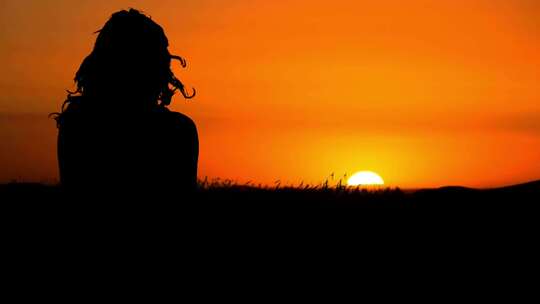 女生孤独背影坐在草地看日落