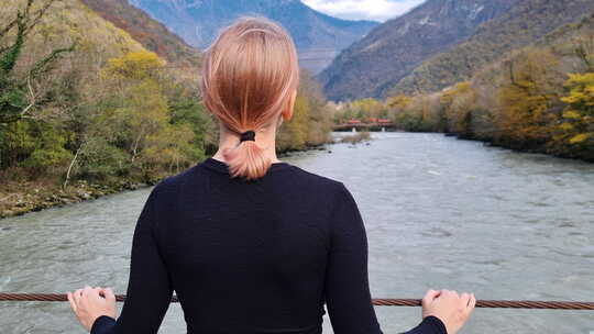 女人站在桥上看着河流和山脉