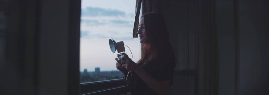 女人在窗前使用相机拍照